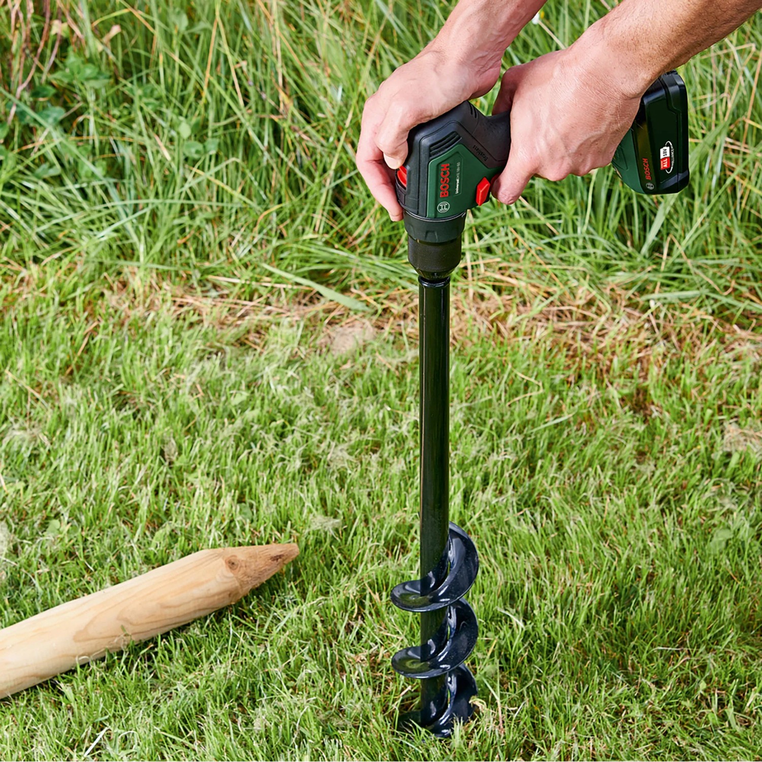 Bosch Akku-Bohrschrauber UniversalDrill 18V-60 im Einsatz mit Erdlochbohrer im Garten.