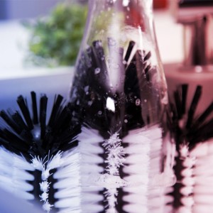 Schwarz-weiße Gläserspülbürste aus Kunststoff reinigt ein Glas im Spülbecken. Ideal für Küchenausstattung & Gastro.