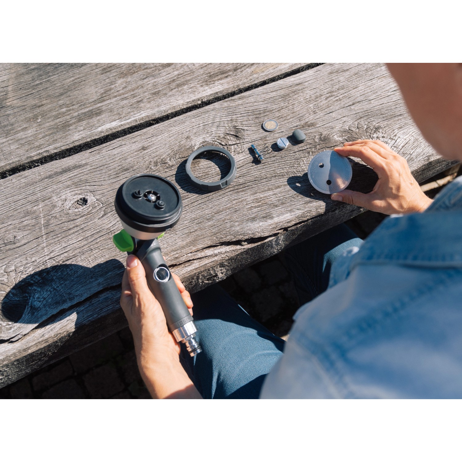 Geka Multibrause Plus 3S Grau, zerlegt auf einer Holzbank. Gartenspritze mit verschiedenen Düsenaufsätzen.