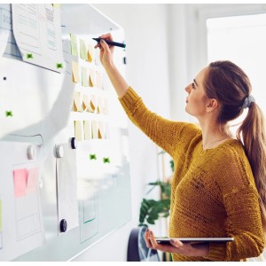 Frau beschreibt Venilia Whiteboard Klebefolie mit Stift und Magneten.