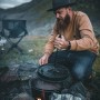 Petromax Dutch Oven Set FT9-T-Scrub: Mann kocht im Outdoor-Feuertopf über offenem Feuer.