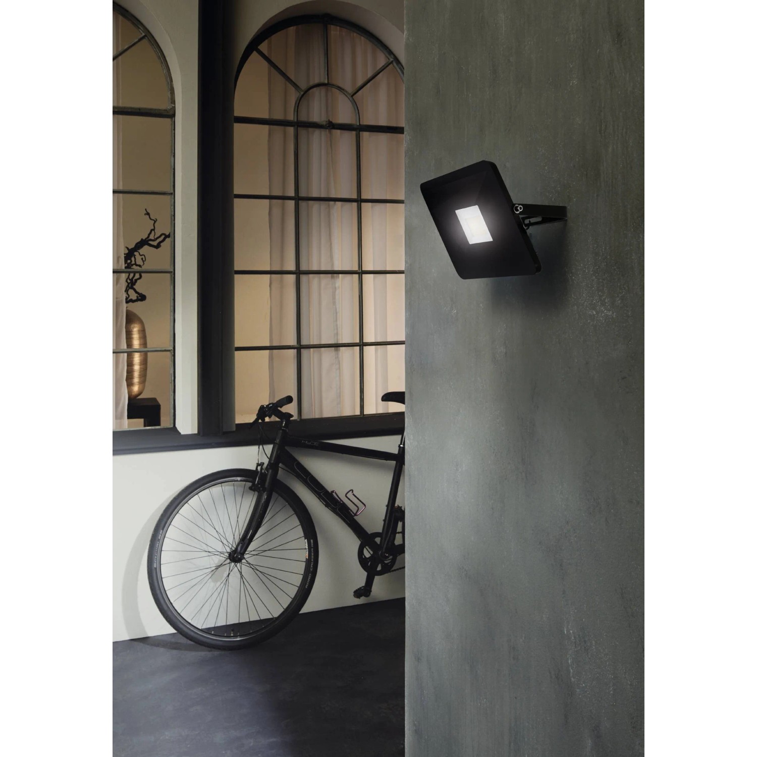 Schwarzer Eglo LED-Wandstrahler Faedo3, 50W, an grauer Wand montiert. Außenstrahler für Haus und Garten.