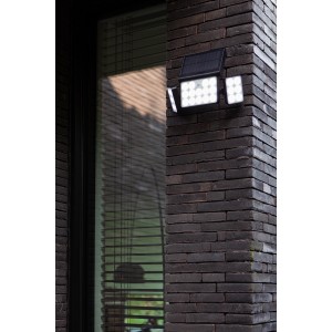 Schwarze Lutec LED-Solarleuchte Tuda mit 3 Leuchten an einer Backsteinwand.