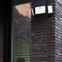 Schwarze Lutec LED-Solarleuchte Tuda mit 3 Leuchten an einer Backsteinwand.