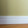 Weiße NOEL & MARQUET Sockelleiste FD11 WALLSTYL an Wand und Holzboden.