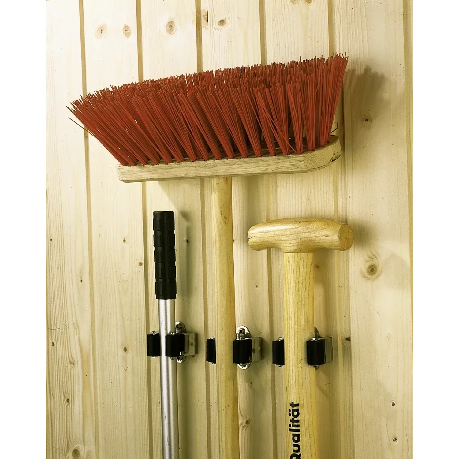 5-teiliges Gerätehalter-Set an einer Holzwand mit Besen, Schaufel und Hammer.