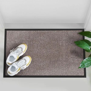 Helle, beige Karat Schmutzfangmatte Rhine 120x180 cm mit Schuhen und Pflanze im Eingangsbereich.