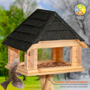 Dobar Vogelhaus aus hellem Kiefernholz mit schwarzem Bitumendach und Futter. Ein Spatz fliegt zum Futterhaus.