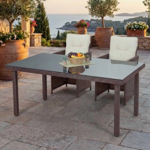 Brauner MCW Poly-Rattan Gartentisch Chieti mit verdunkelter Glasplatte auf einer Terrasse.