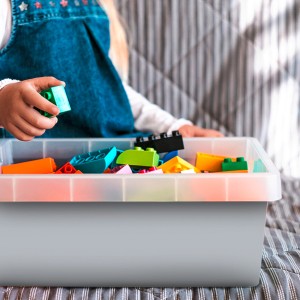 Klebefolie Wolkengrau: Kind spielt mit bunten Bauklötzen in grauer Aufbewahrungsbox.