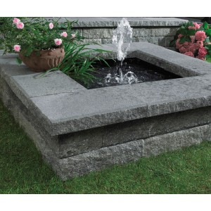 Bruchsteinmauer mit Abdeckplatte in Grau-Nuanciert und kleinem Springbrunnen im Garten.