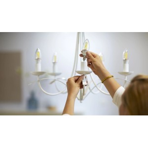 Frau schraubt Philips Smart LED-Filament Leuchtmittel in einen Kronleuchter.