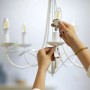 Frau schraubt Philips Smart LED-Filament Leuchtmittel in einen Kronleuchter.