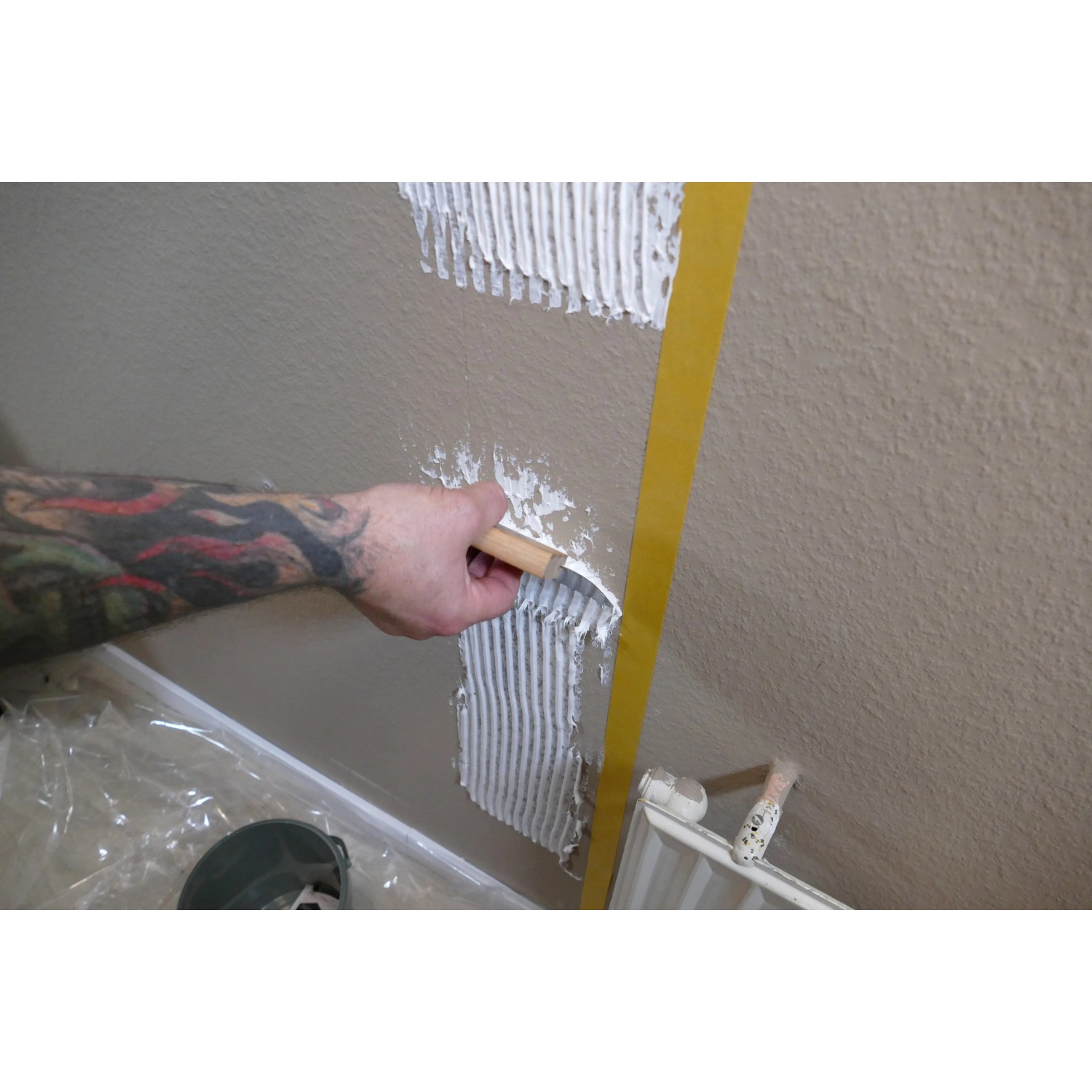Anwendung von Soudal Fix All Floor & Wall Kleber mit Spachtel auf einer Wand.