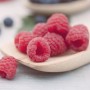 Frische, rote Himbeeren der Sorte Rubus Idaeus Meeker auf einem Holzlöffel.