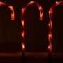Drei leuchtende Zuckerstangen mit rot-weißem Spiralmuster als Weihnachtsdekoration.