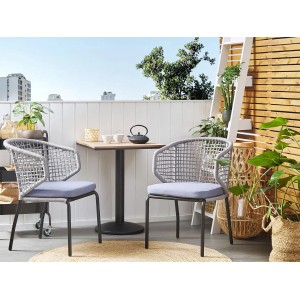Quadratischer Beliani Gartentisch PALMI in heller Holzoptik mit zwei Stühlen auf einem Balkon.