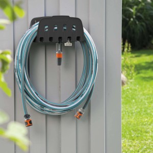 Gardena Wandschlauchhalter mit aufgerolltem Gartenschlauch und Bewässerungsaufsätzen.