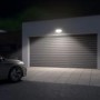 Graue LED Außenwandleuchte mit Bewegungsmelder an Garage beleuchtet Einfahrt.