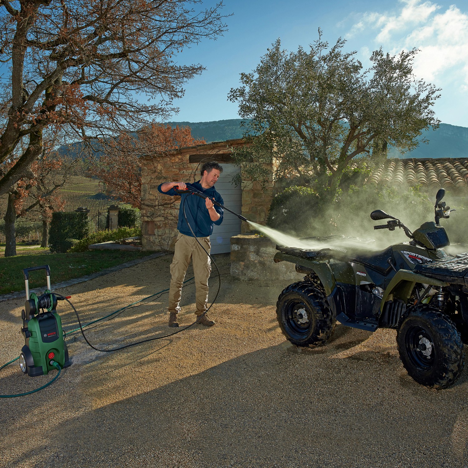 Mann reinigt Quad mit Bosch Hochdruckreiniger AdvancedAquatak 140 im Außenbereich.