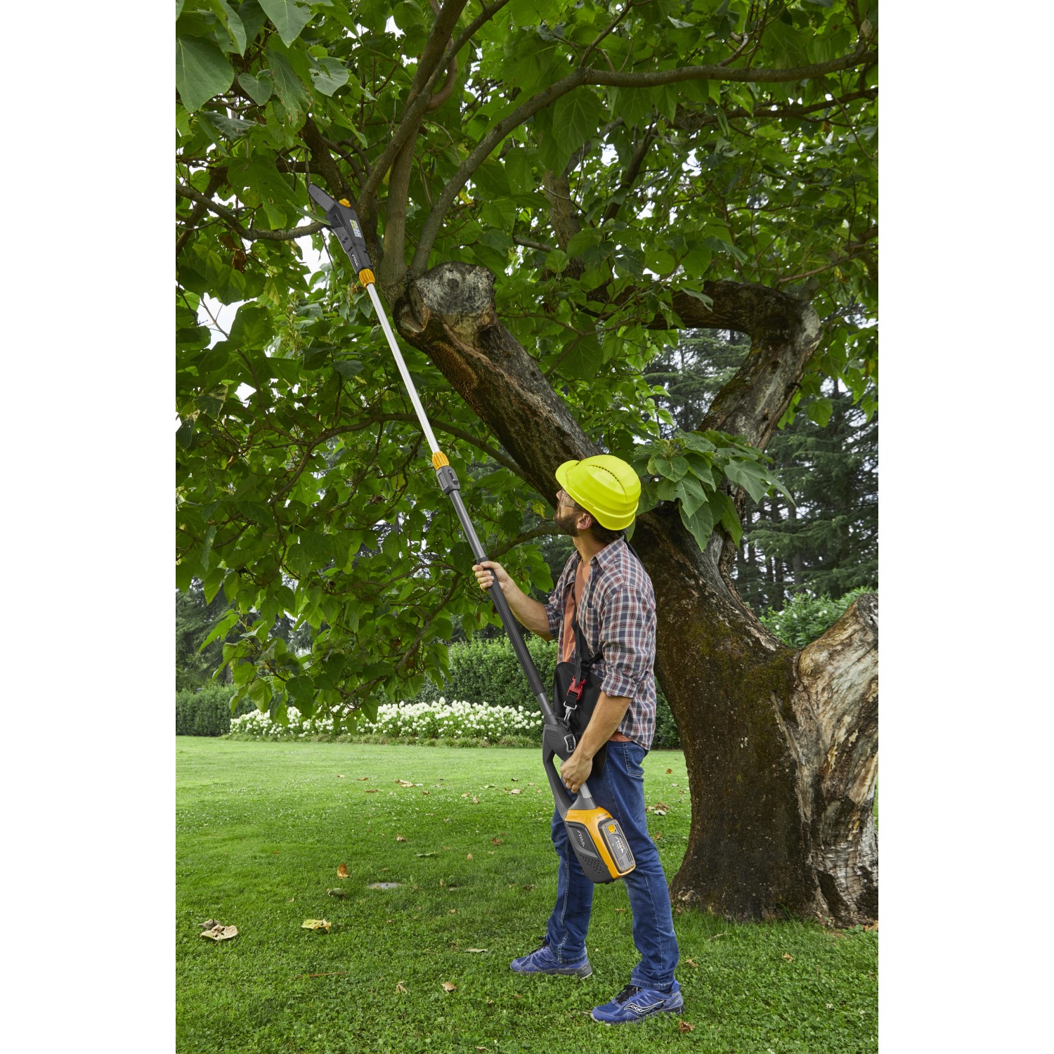 Mann schneidet Baum mit Stiga Akku-Multitool MT 500e Hochentaster im Garten.