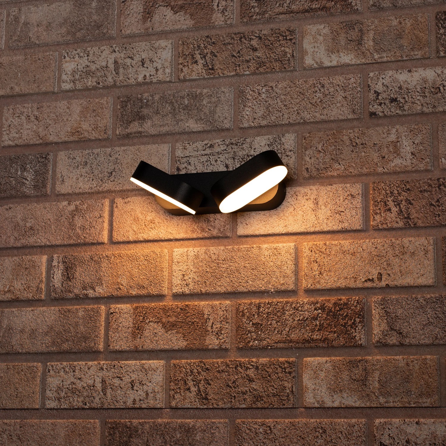 Schwarze LED`s light Außenwandleuchte Oval mit zwei drehbaren Leuchten an einer Backsteinwand.