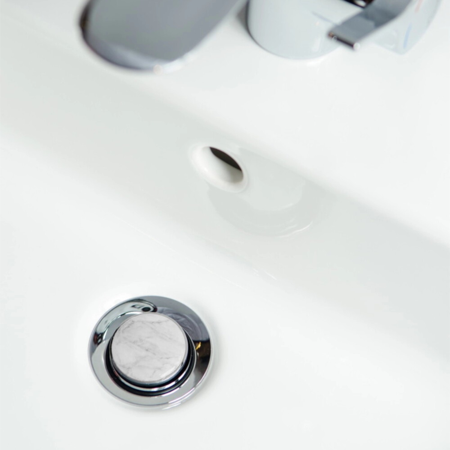 Sanilo Waschbeckenstöpsel mit Marmor-Design im weißen Waschbecken.