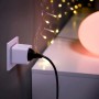 Philips Hue SmartPlug im Einsatz: Weißer Zwischenstecker in Steckdose, Lampe im Hintergrund.