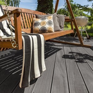 Home Deluxe WPC-Terrassendielen Samana Hellgrau auf Terrasse mit Gartenschaukel und Grill.