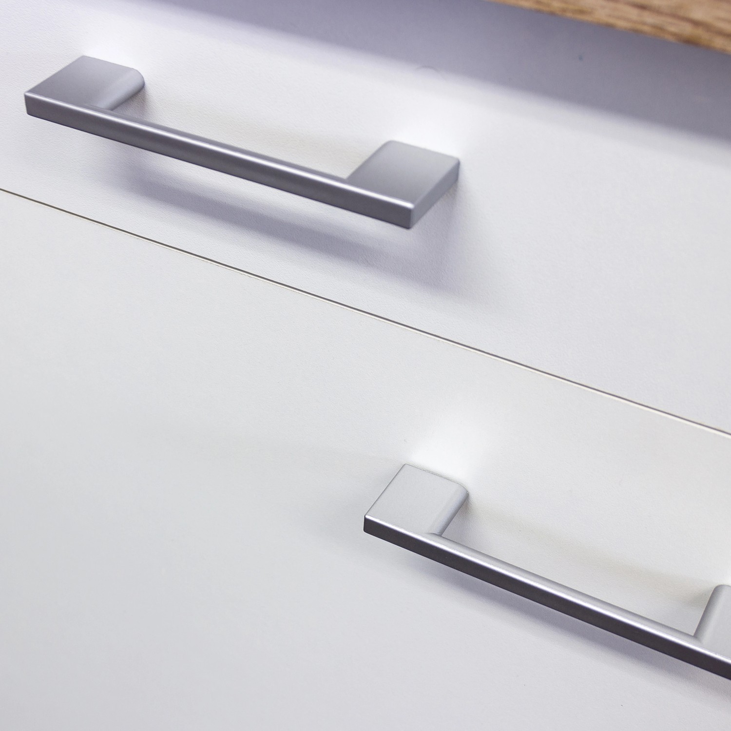 Detailaufnahme: Silberfarbene Griffe an weißen Schrankfronten der Flex-Well Küchenzeile Florida.