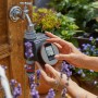 Gardena Bewässerungscomputer Flex am Wasserhahn, bedient von Händen. Automatische Gartenbewässerung.