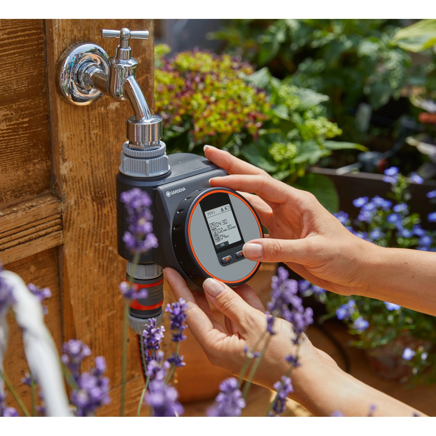 Gardena Bewässerungscomputer Flex am Wasserhahn, bedient von Händen. Automatische Gartenbewässerung.