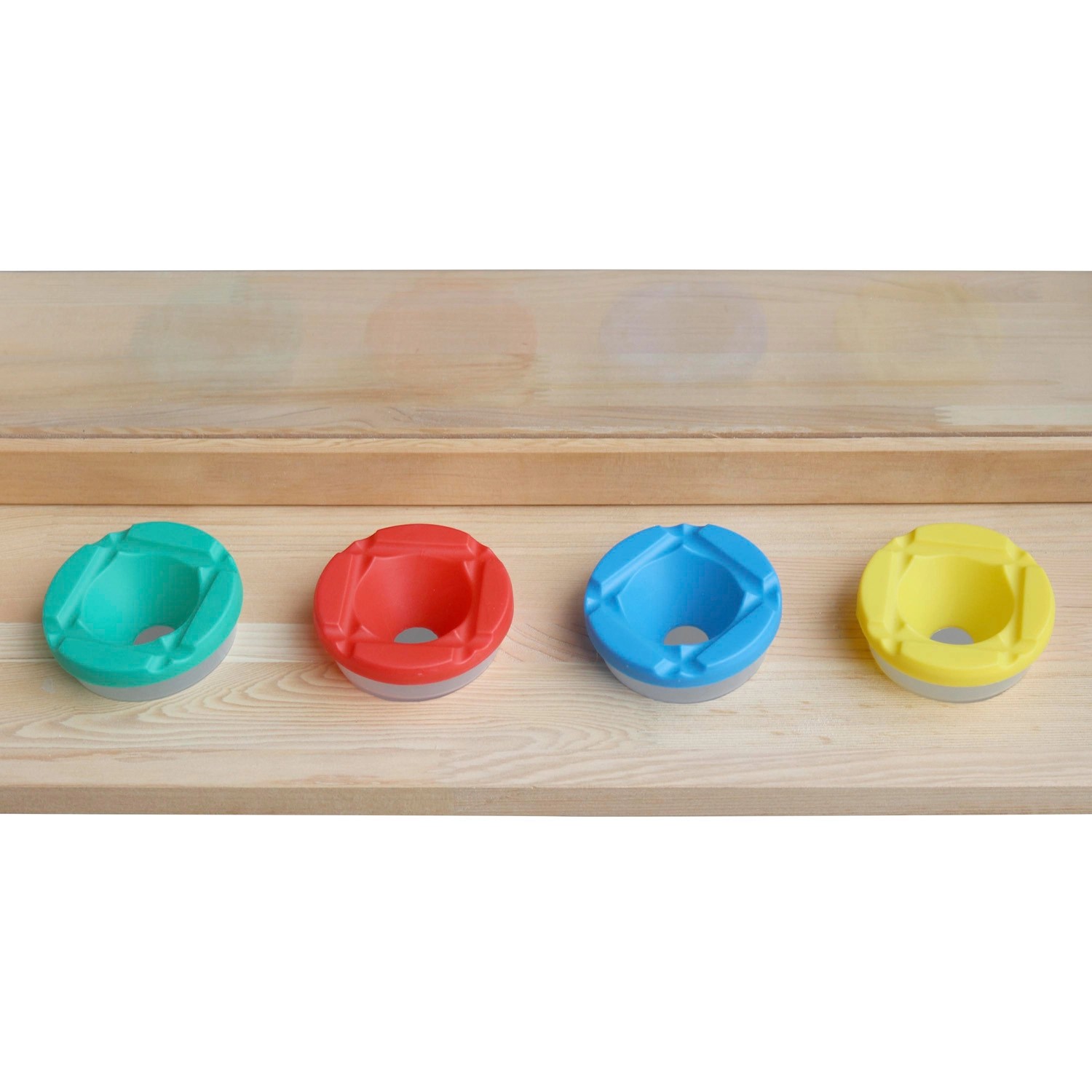 Axi Kinderstaffelei Zubehör: Vier farbige Farbbehälter (Grün, Rot, Blau, Gelb) auf Ablage.