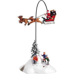 Weihnachtsdekoration: Weihnachtsmann im Schlitten über Winterdorf mit Kindern und Schneemann.