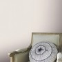 Erismann Vliestapete Versailles Celeste helltaupe an Wand über Sessel mit Kissen.