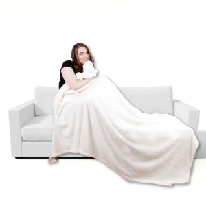 Frau kuschelt in eine champagnerfarbene Bestgoodies Mikrofaser Decke auf einem Sofa.