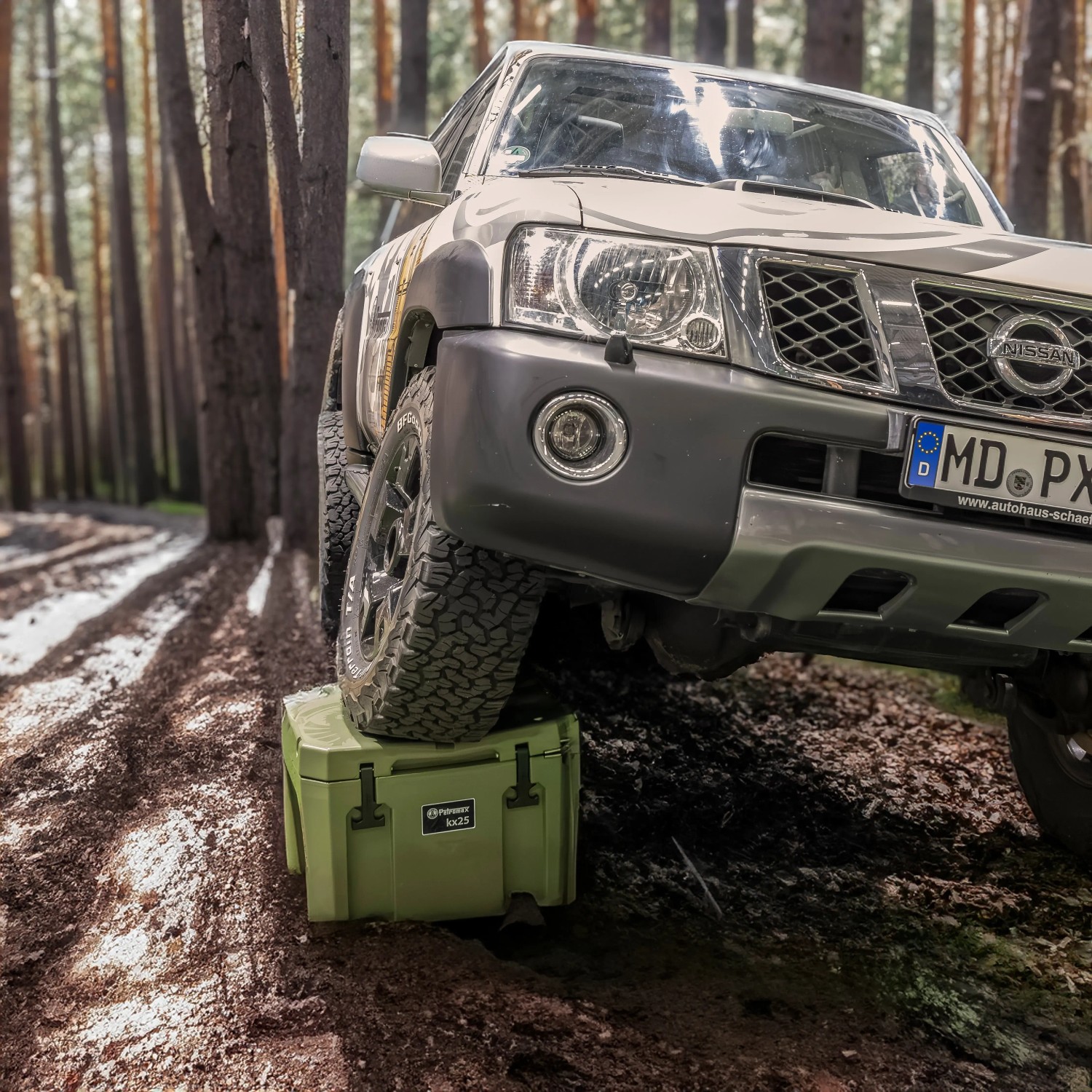 Petromax Kühlbox Sand 50L unter Offroad-Fahrzeug im Wald. Robuste Kühlbox für Camping und Outdoor-Abenteuer.
