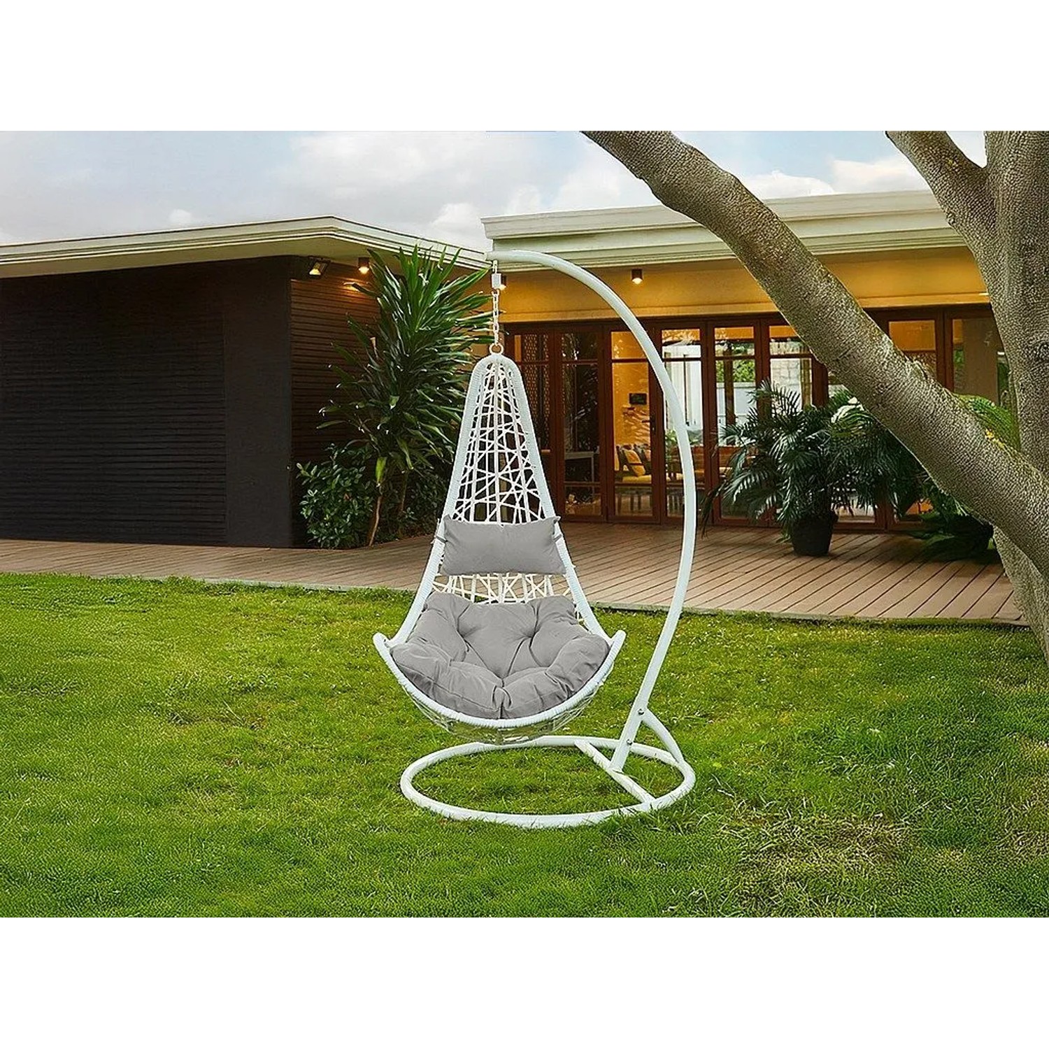 Weißer Vente-unique Orosi Hängesessel aus Polyrattan mit grauen Kissen auf grünem Rasen im Garten.