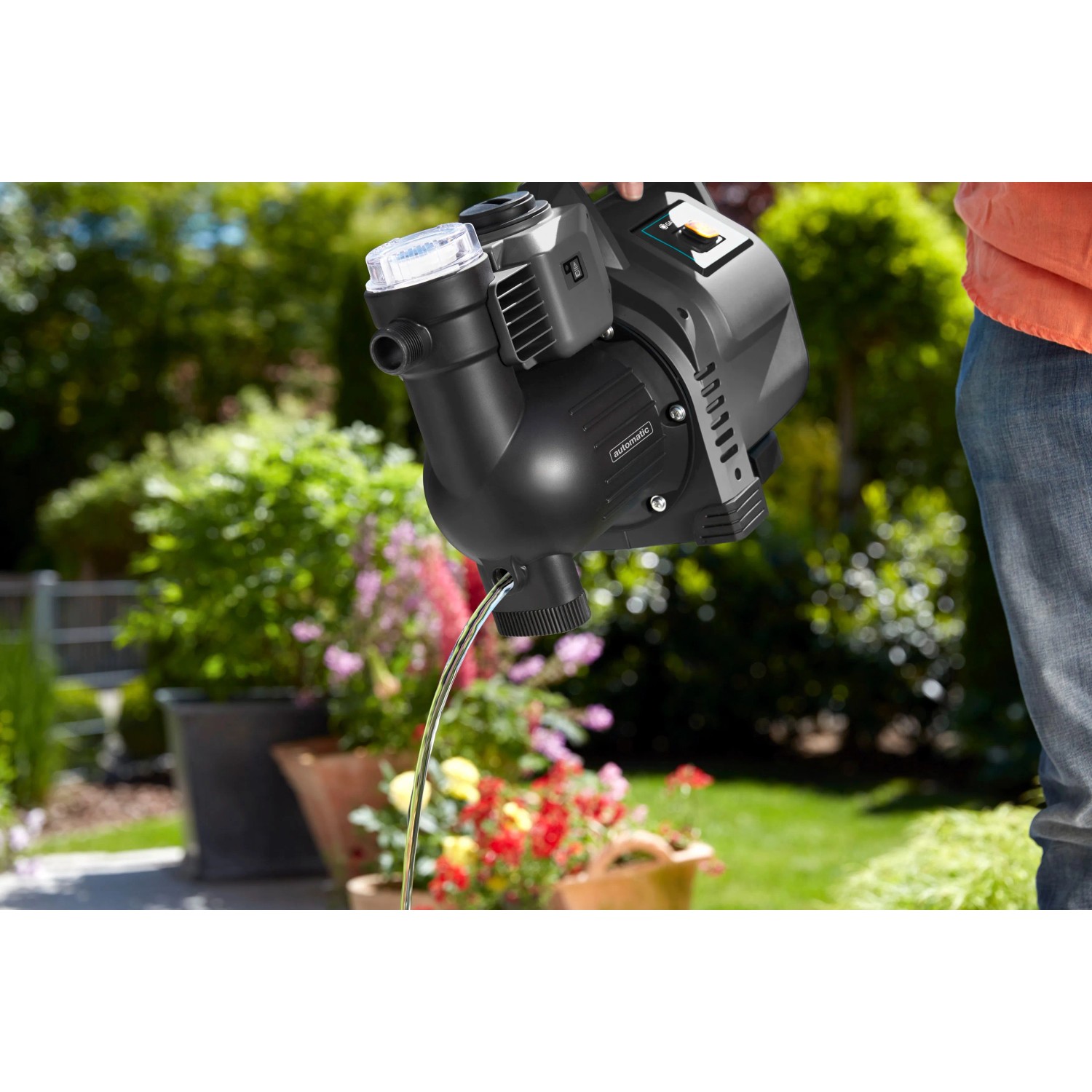 Gardena Haus- und Gartenautomat 3500/4 in Aktion: Wasser fließt aus der schwarzen Pumpe im Garten.