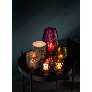 Verschiedene Teelichthalter der Serie Dark Wonder aus Glas in Grün-, Gold- und Lilatönen auf einem Tisch.