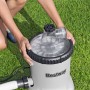 Bestway Polysphere Filterpumpe mit Filterbällen auf Rasen. Hände justieren die Pumpe für sauberes Poolwasser.