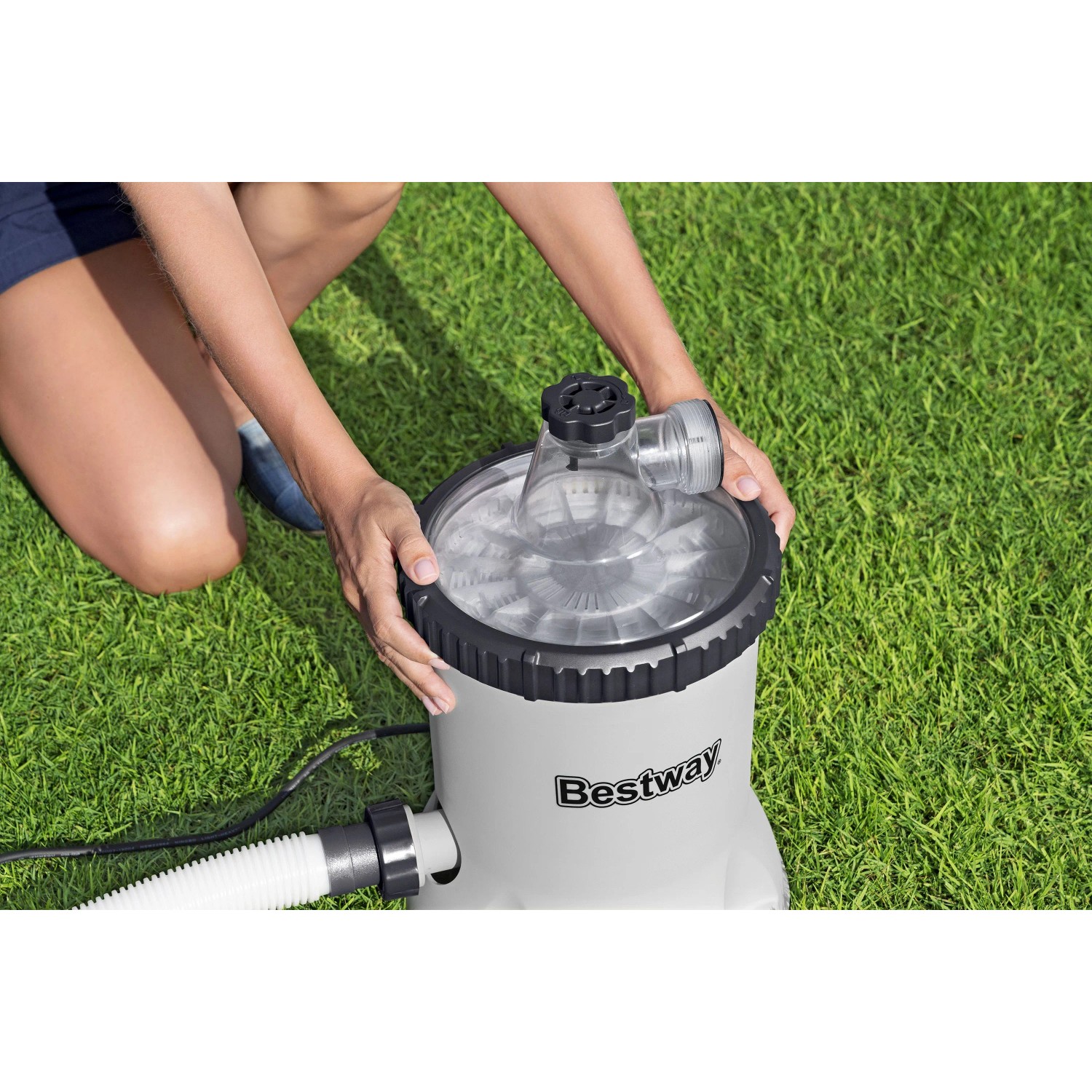 Bestway Polysphere Filterpumpe mit Filterbällen auf Rasen. Hände justieren die Pumpe für sauberes Poolwasser.