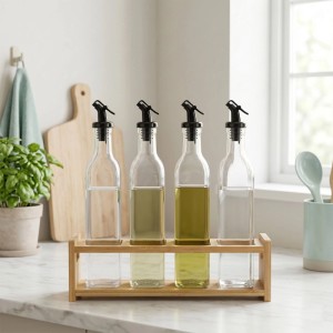Relaxdays Ölflaschen 4er Set aus Glas mit schwarzen Tropf-Ausgießern im Bambushalter auf Küchenarbeitsplatte.
