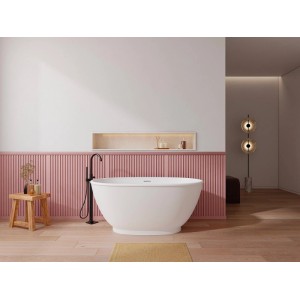 Weiße, ovale freistehende Badewanne Mobula in modernem Bad mit schwarzer Armatur und rosa Wandverkleidung.