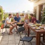Gruppe sitzt auf schwarzen Sekey Rattan Gartenstühlen (6er Set) beim Grillen auf dem Balkon.