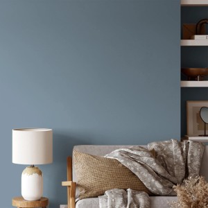 Wand in Delftblau mit V&CO Premium-Innenfarbe Dead Flat Matt. Wohnzimmer-Szene mit Lampe und Sofa.