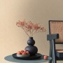 A.S. Creation Vliestapete Uni Struktur beige-gelb an Wand, Tisch mit Deko im Raum.