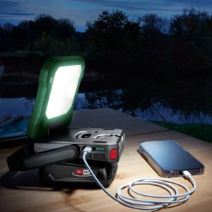 Akku-Lampe EasyLight18V-400 Solo leuchtet hell auf Holztisch im Dunkeln, lädt Smartphone. Ideal für Outdoor-Beleuchtung.