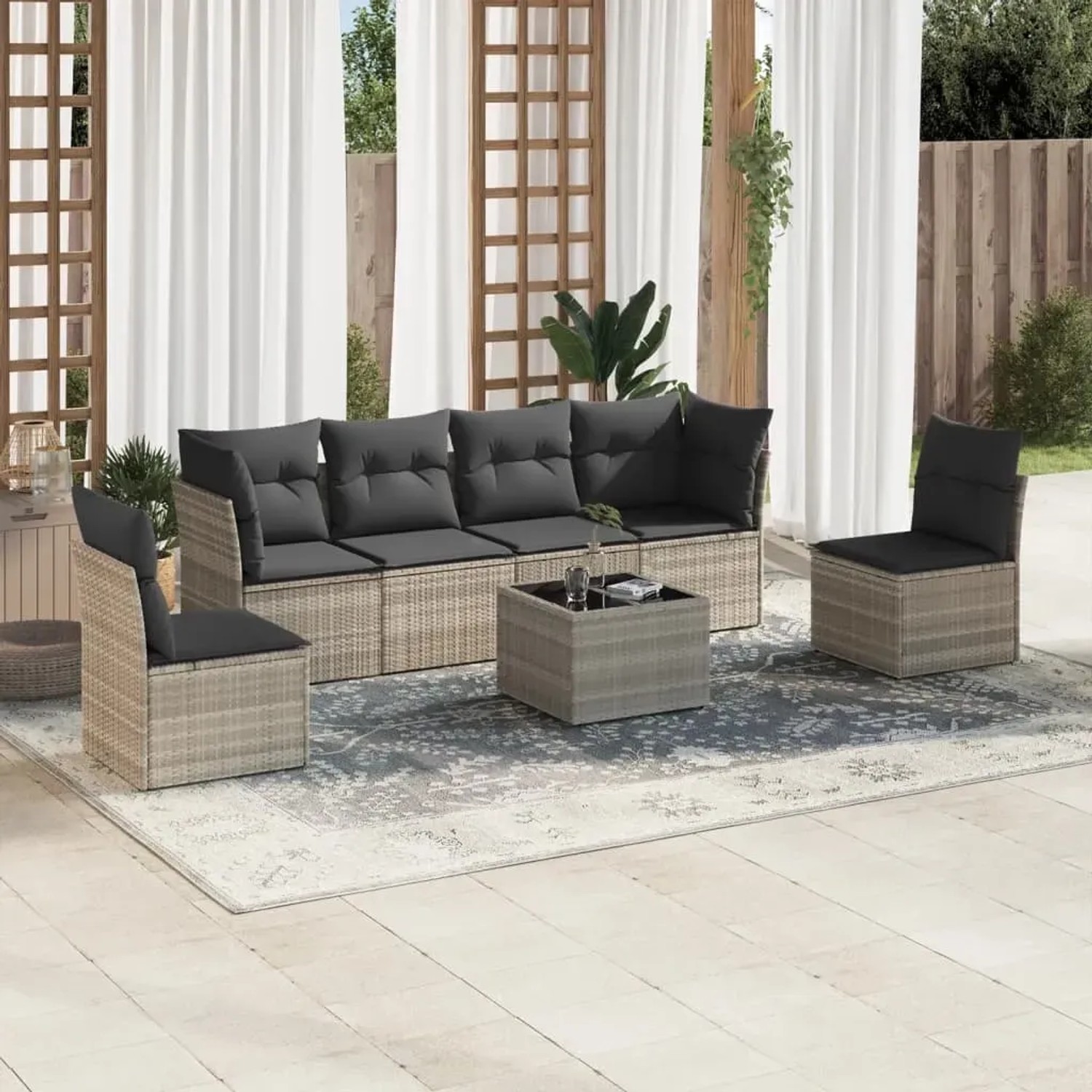 Hellgraue 7-tlg. Garten-Sofagarnitur aus Poly Rattan mit dunklen Kissen und Tisch mit Glasplatte.