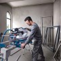 Mann bedient Bosch Professional Kapp- und Gehrungssäge GCM 340-305 D. Blaue Säge mit Verlängerungen für präzise Holzarbeiten.